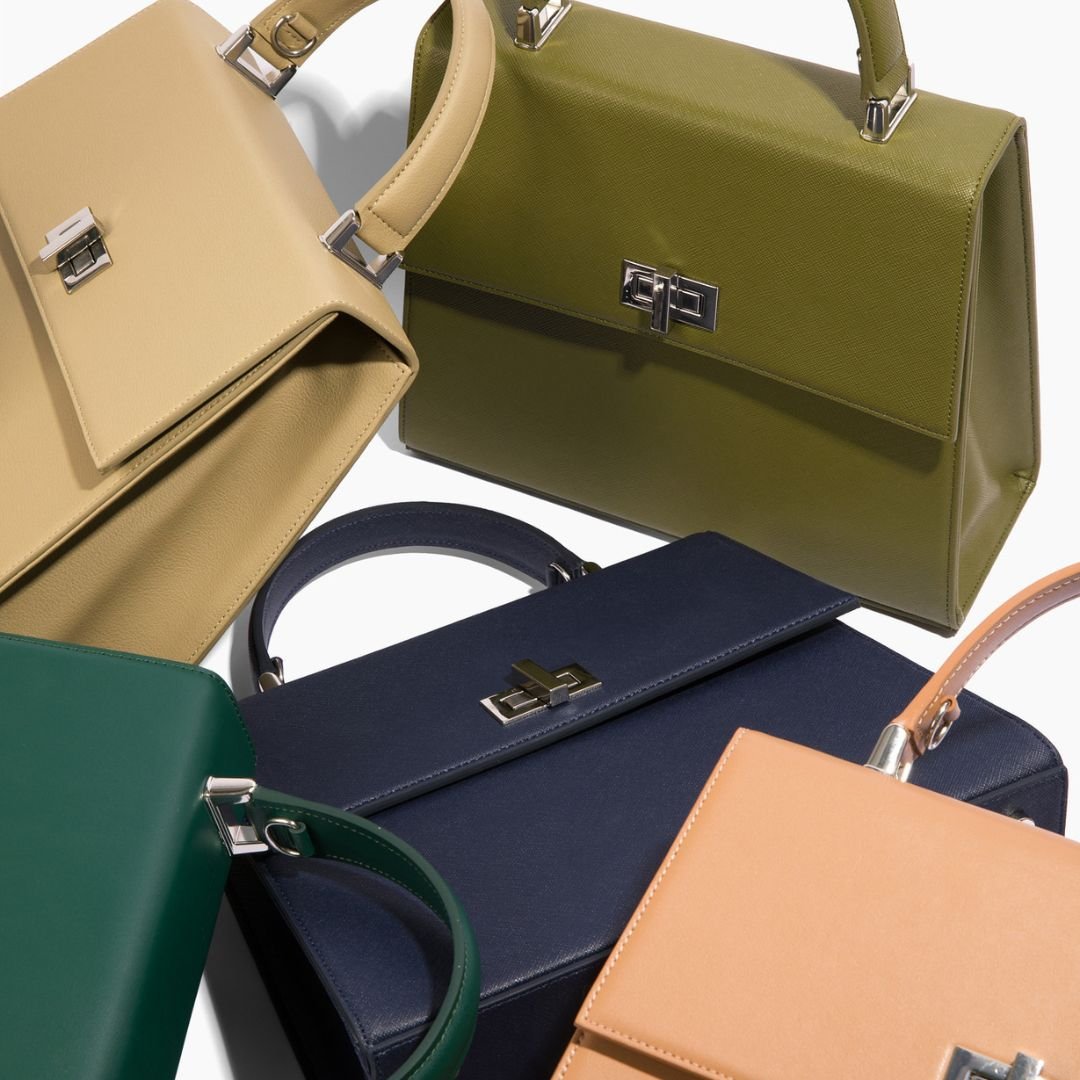 A collection of Carter Wade's She-EO handbags in various elegant colors, including dark green, navy blue, beige, and olive. Each bag showcases its structured design, high-quality vegan leather, and premium Italian hardware, emphasizing luxury and sustainability.
