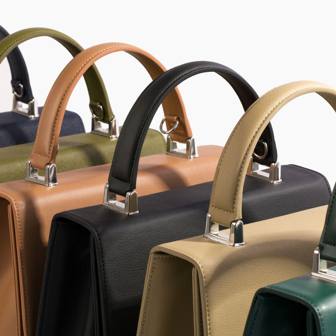 A lineup of Carter Wade's She-EO handbags, captured from a back angle to highlight the refined craftsmanship of the structured handles, metallic details, and smooth vegan leather finish. A statement piece for conscious luxury.