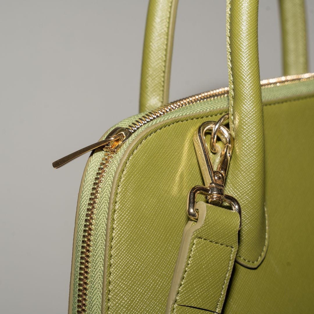 A close-up of the bag’s gold zipper and detachable strap hardware. The high-quality Italian hardware complements the luxurious cactus leather and ensures a secure closure.