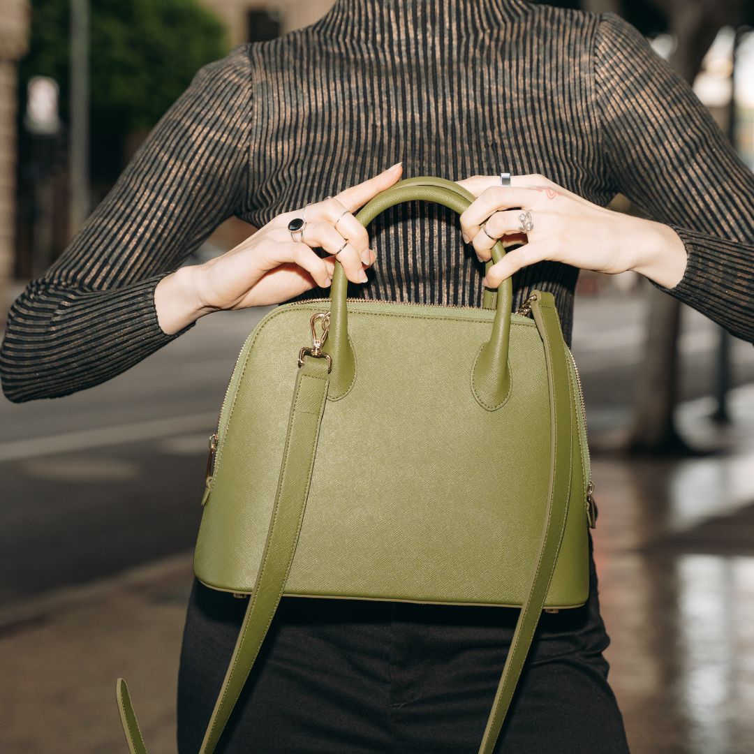 A woman holding Ms. Lady Luck in Olive Green, showcasing its top-handle design and rich cactus leather texture. The bag’s refined elegance complements both casual and formal outfits.