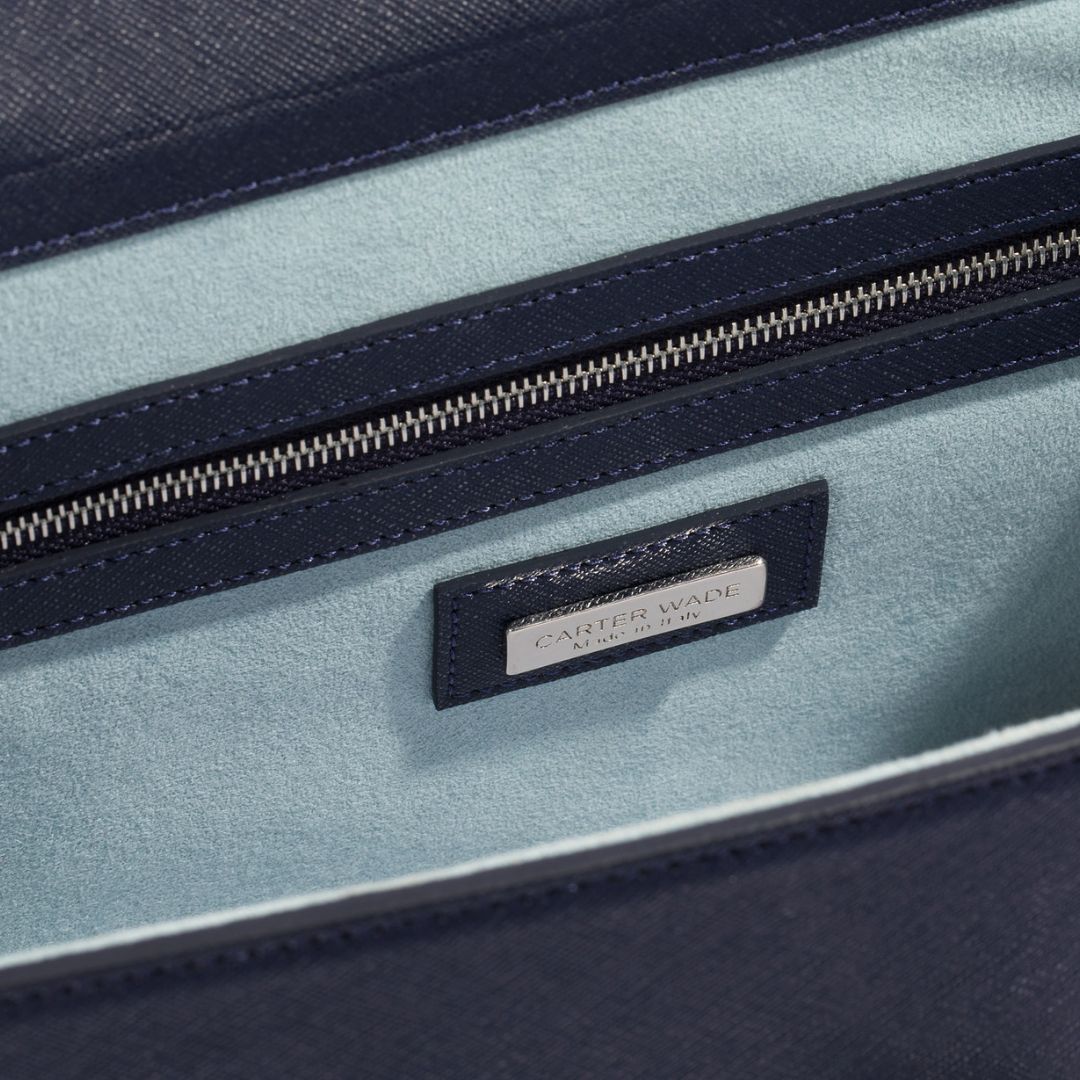 An interior shot of The She-EO handbag, featuring a soft Montauk blue vegan suede lining, a zippered compartment, and a Carter Wade logo plaque. Thoughtfully designed for organization and effortless elegance.