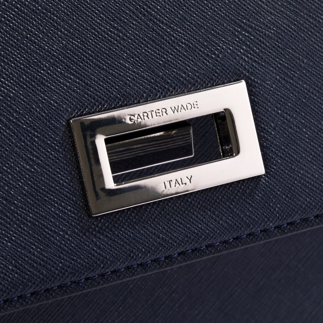 A detailed view of The She-EO handbag’s turn-lock closure, engraved with the Carter Wade logo and "Italy," signifying premium craftsmanship. The polished silver finish complements the navy blue cactus leather beautifully