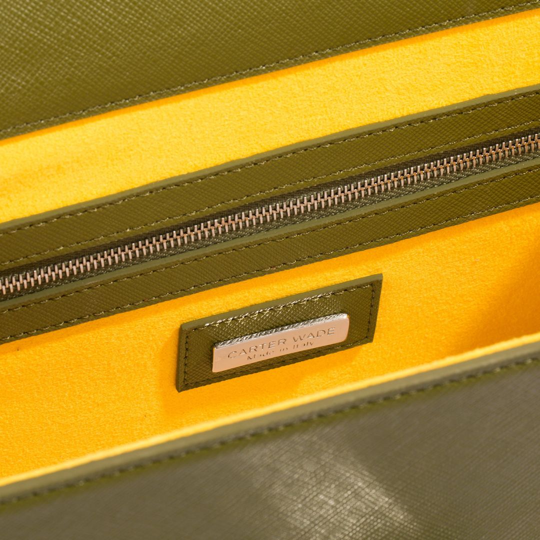 A close-up of the interior of The She-EO handbag in Olive Cactus Leather, showcasing its vibrant yellow vegan suede lining, a zippered pocket, and a sleek Carter Wade logo plaque, emphasizing luxury craftsmanship and thoughtful design