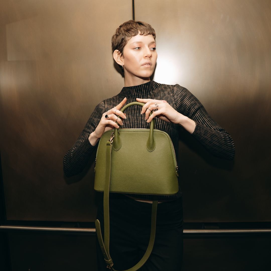A stylish woman poses with the Ms. Lady Luck handbag in an elevator, reflecting its effortless sophistication.