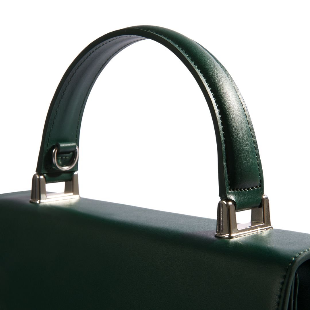 Close-up of the dark green handbag handle with sleek silver hardware, showcasing the elegant craftsmanship of Carter Wade