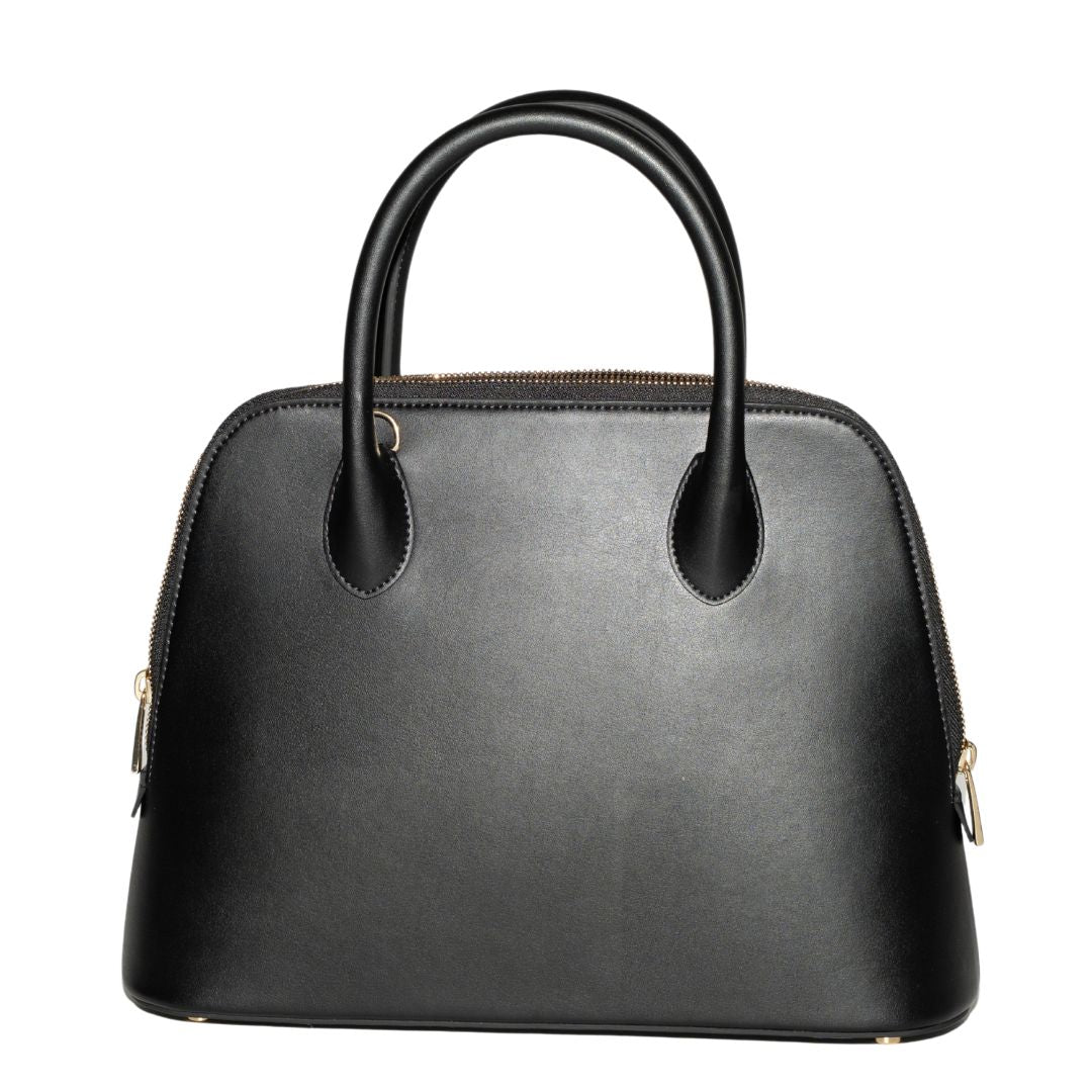 A sleek black structured handbag, Ms. Lady Luck in Noir, displayed against a white background. Crafted from smooth grape leather with a timeless silhouette, this luxury handbag features a curved top handle design and premium gold hardware.