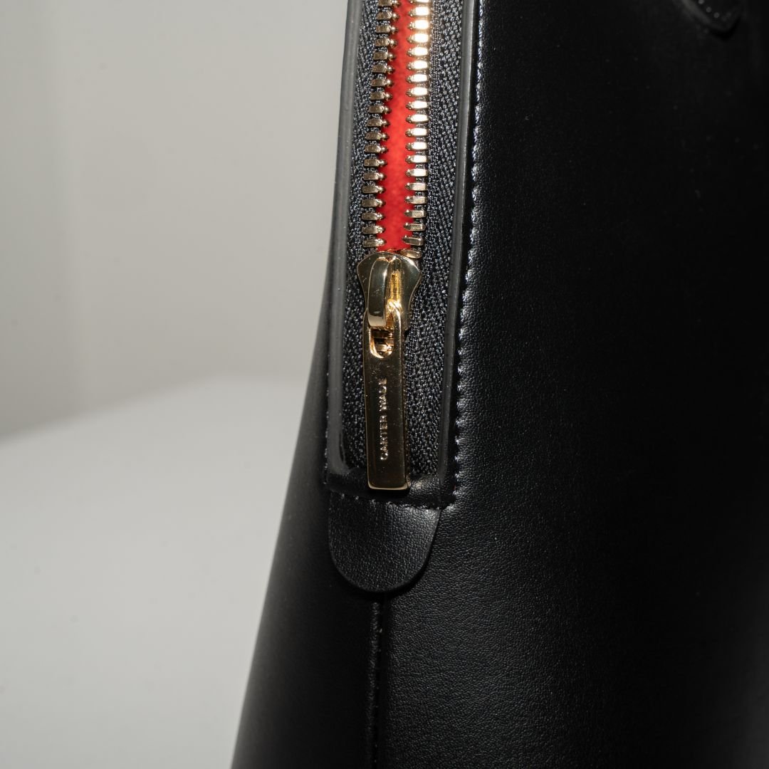  A macro shot of the Ms. Lady Luck handbag’s gold zipper and structured leather finish. The high-quality vegan leather is complemented by precision stitching and polished gold hardware for a sophisticated look.